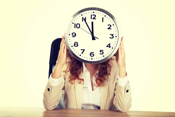 Businesswoman with clock by a desk. — Stock Photo, Image