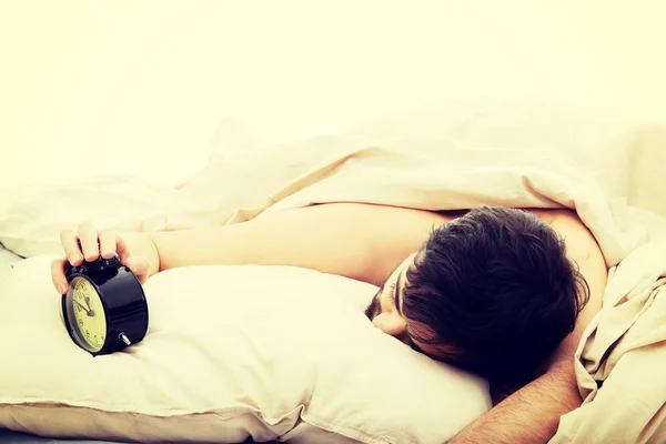 Exhausted man being awakened by an alarm clock. — Stock Photo, Image