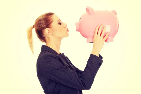 Glückliche Geschäftsfrau küsst ein Sparschwein. — Stockfoto