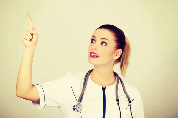 Jeune médecin femme pointant vers le haut . — Photo