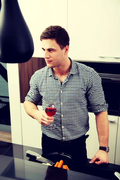 Человек с бокалом вина на кухне . — стоковое фото