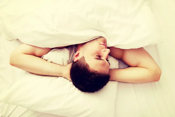 Schöner junger Mann liegt im Bett. — Stockfoto