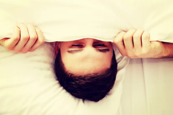 Mann versteckt sich im Bett unter Laken. — Stockfoto