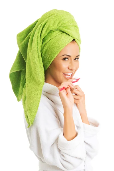 Woman in bathrobe brushing teeth — Stock Photo, Image