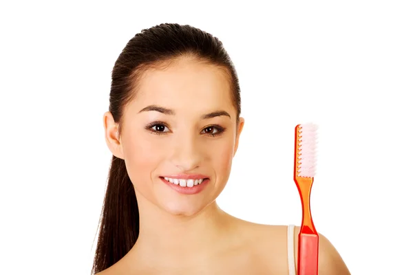 Mujer joven sosteniendo un cepillo de dientes grande . —  Fotos de Stock