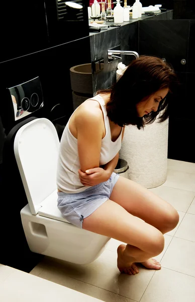Caucasian woman is sitting on the toilet. — Stock Photo, Image