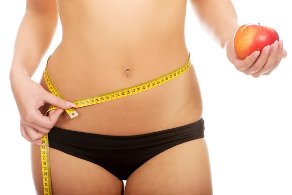 Woman with apple measuring her waist. — Stock Photo, Image