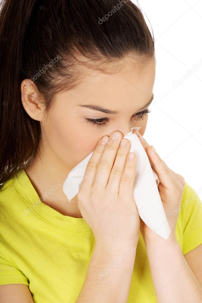 Teen woman sneezing to tissue.