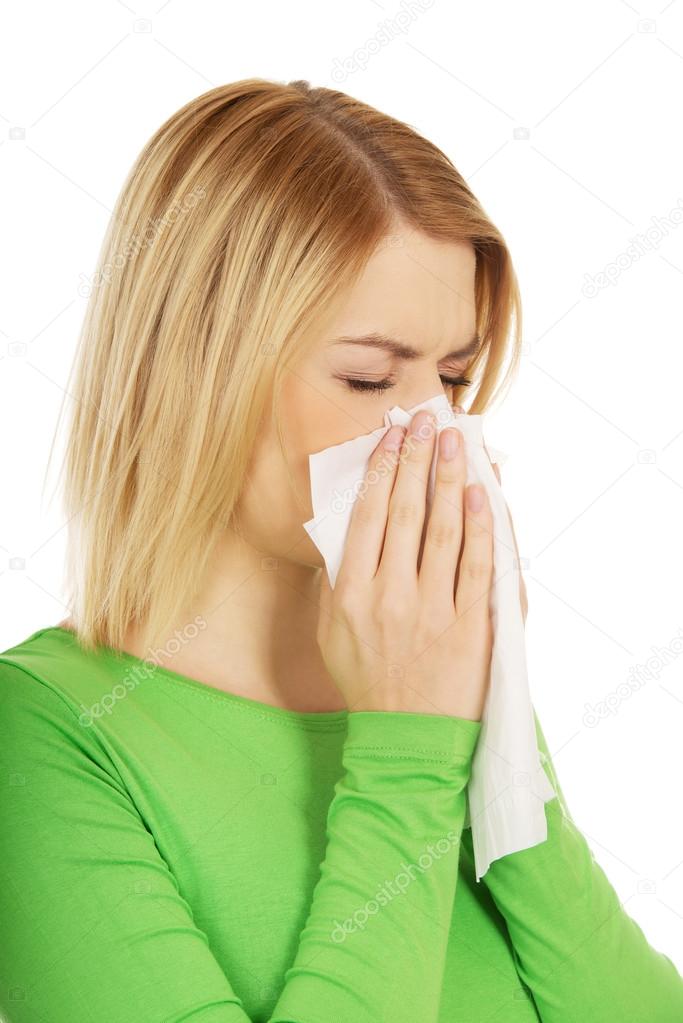 Woman sneezing to tissue.