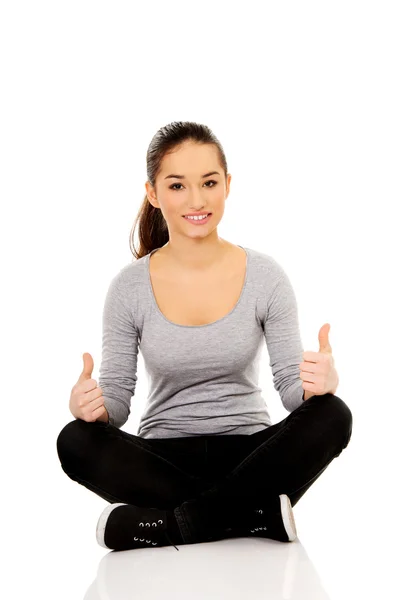 Woman sitting cross legged with thumbs up. — Stock Photo, Image