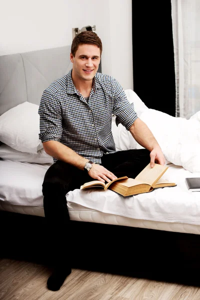 Un hombre con un libro en su cama . — Foto de Stock