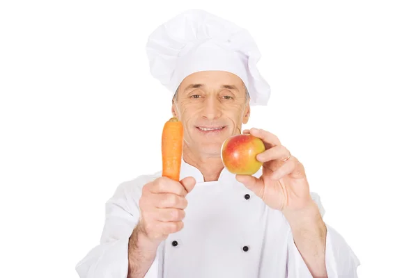 Manliga chef med ett äpple och morot — Stockfoto