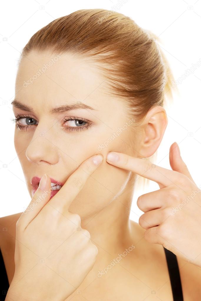 Young woman squeezes her acne.
