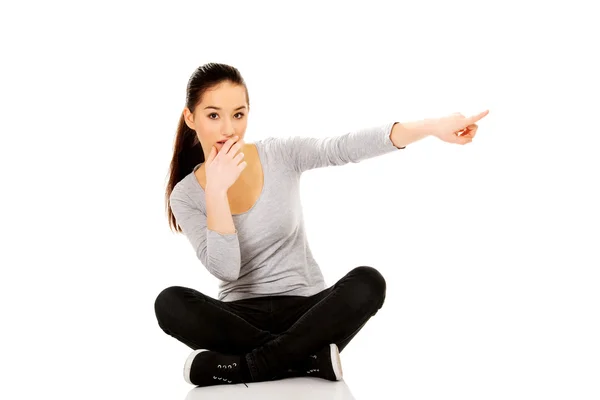 Vrouw zitten cross legged wijzen opzij. — Stockfoto