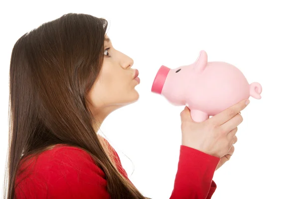 Ung kvinna kysser en piggybank. — Stockfoto