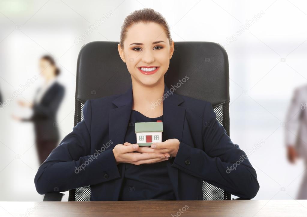 Happy real estate agent, holding a house model