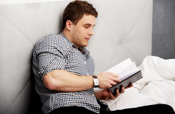 Un hombre reflexivo leyendo una nota en su cama . — Foto de Stock