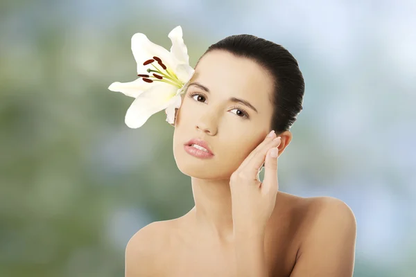 Frau mit gesunder Haut und Lilienblüte — Stockfoto