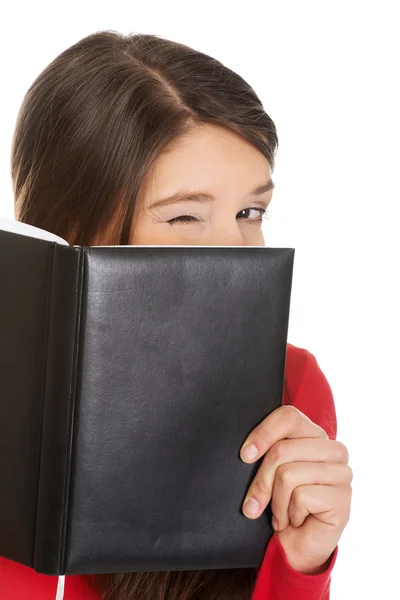 Woman hiding her face behind a notebook. — Stock Photo, Image