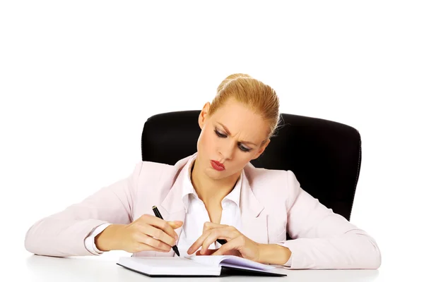 Pensive business woman taking notes behind the desk — Stock Photo, Image