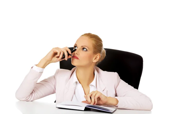 Pensive zakenvrouw neemt notities achter het bureau — Stockfoto
