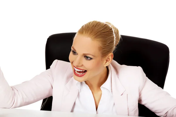 Heureuse femme d'affaires assise derrière le bureau — Photo