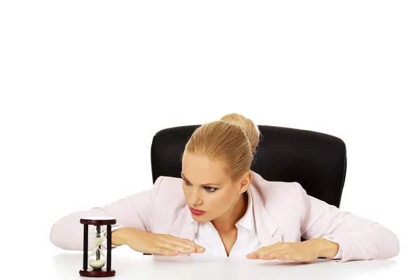 Mulher de negócios sentada atrás da mesa e à procura de sandglass — Fotografia de Stock