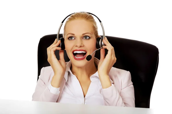 Smile helpline operator sitting behind the desk and talking through a headphones — Stock Photo, Image