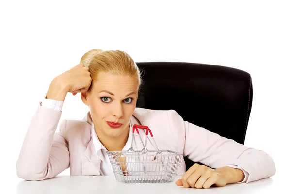 Sorridi donna d'affari seduta dietro la scrivania con piccolo cesto della spesa — Foto Stock