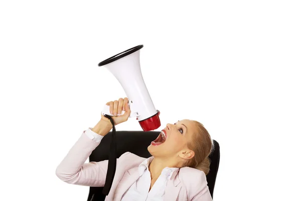 Bizneswoman siedzi za biurkiem i krzyczy przez megafon — Zdjęcie stockowe