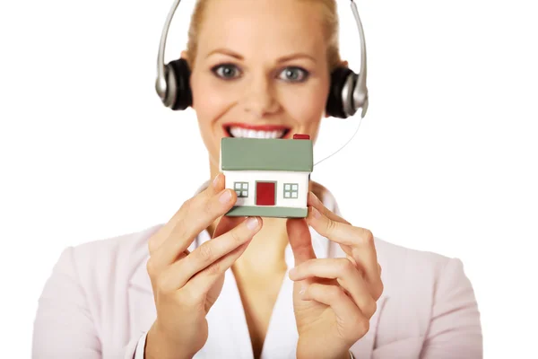 Mladá podnikatelka v headsetu drží model domu — Stock fotografie