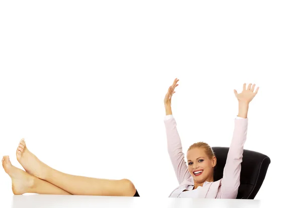 Glückliche Geschäftsfrau mit Händen hoch, die Beine auf dem Schreibtisch haltend — Stockfoto