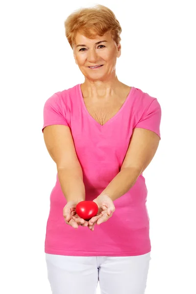 Oude lachende vrouw met rode speelgoed hart — Stockfoto