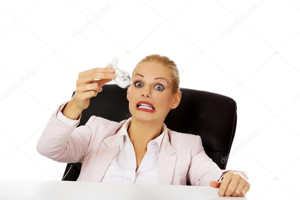 Business woman sitting behind the desk and holding a toy plane