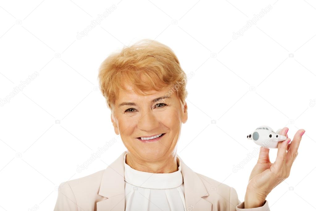 Smile elderly elegant woman holding a toy plane