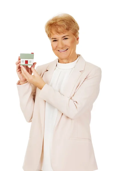 Glimlach oudere vrouw holding huis model — Stockfoto