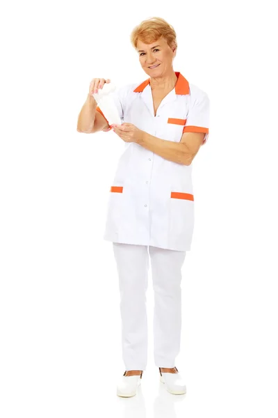 Sorriso anziano medico femminile o infermiere tiene benda — Foto Stock