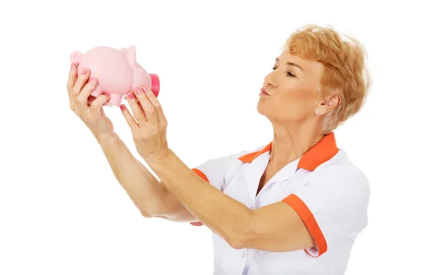 Úsměv starší ženský lékař nebo zdravotní sestra drží prasátko — Stock fotografie