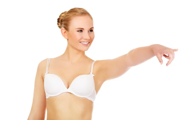 Mujer joven en sujetador blanco apuntando para copyspace o algo así —  Fotos de Stock