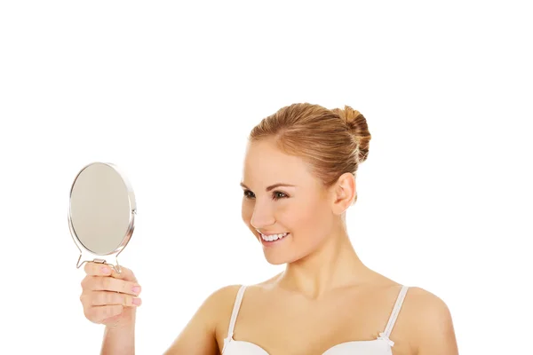 Молодая красивая женщина, смотрящая в зеркало — стоковое фото