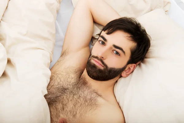 Junger muskulöser Mann liegt im Bett. — Stockfoto