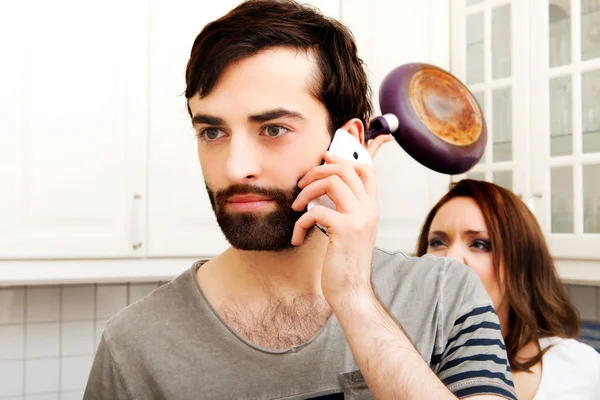 Angry young woman hitting men with frying pan. — Stock Photo, Image