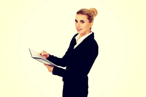 Young businessoman holding notebook and writes something — Stock Photo, Image