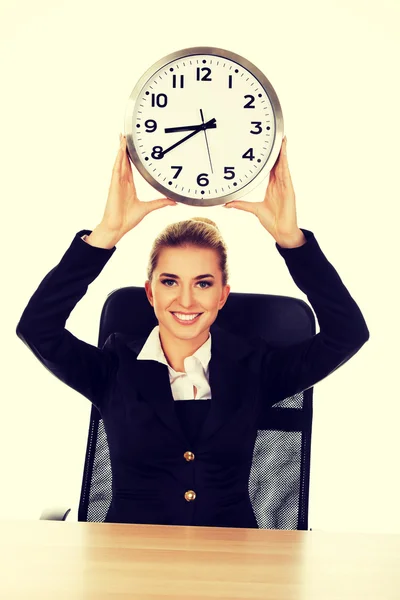 Happy affärskvinna med klocka bakom skrivbordet — Stockfoto