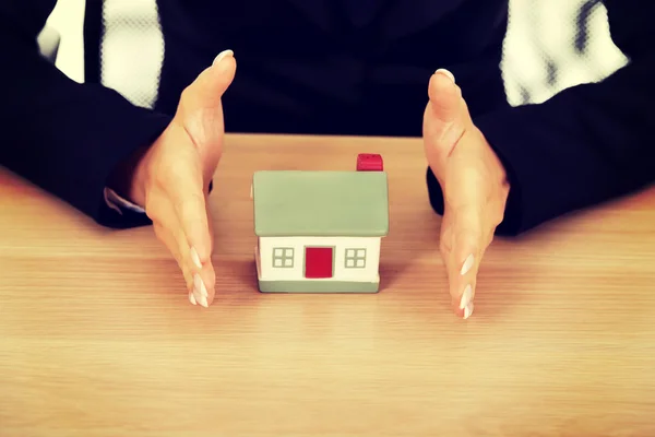 Empresária com pequena casa atrás da mesa — Fotografia de Stock