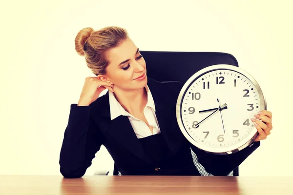 Happy businesswoman with clock behind the desk — Stock Photo, Image