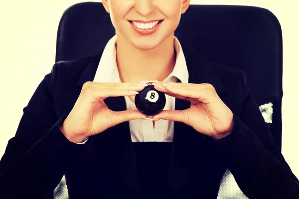 Businesswoman holding eight billiard ball by a desk — Stock Photo, Image