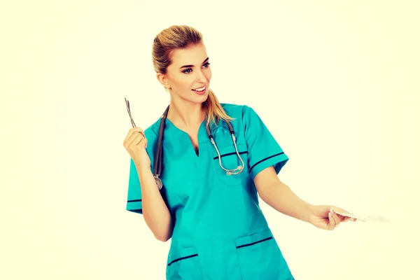 Vrouwelijke verpleegster holding gaas en schaar — Stockfoto
