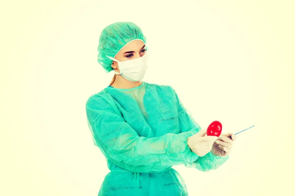 Young female cardiologist surgeron holding heart and scalpel — Stock Photo, Image