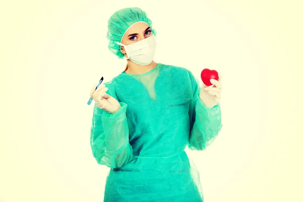 Young female cardiologist surgeron holding heart and scalpel — Stock Photo, Image